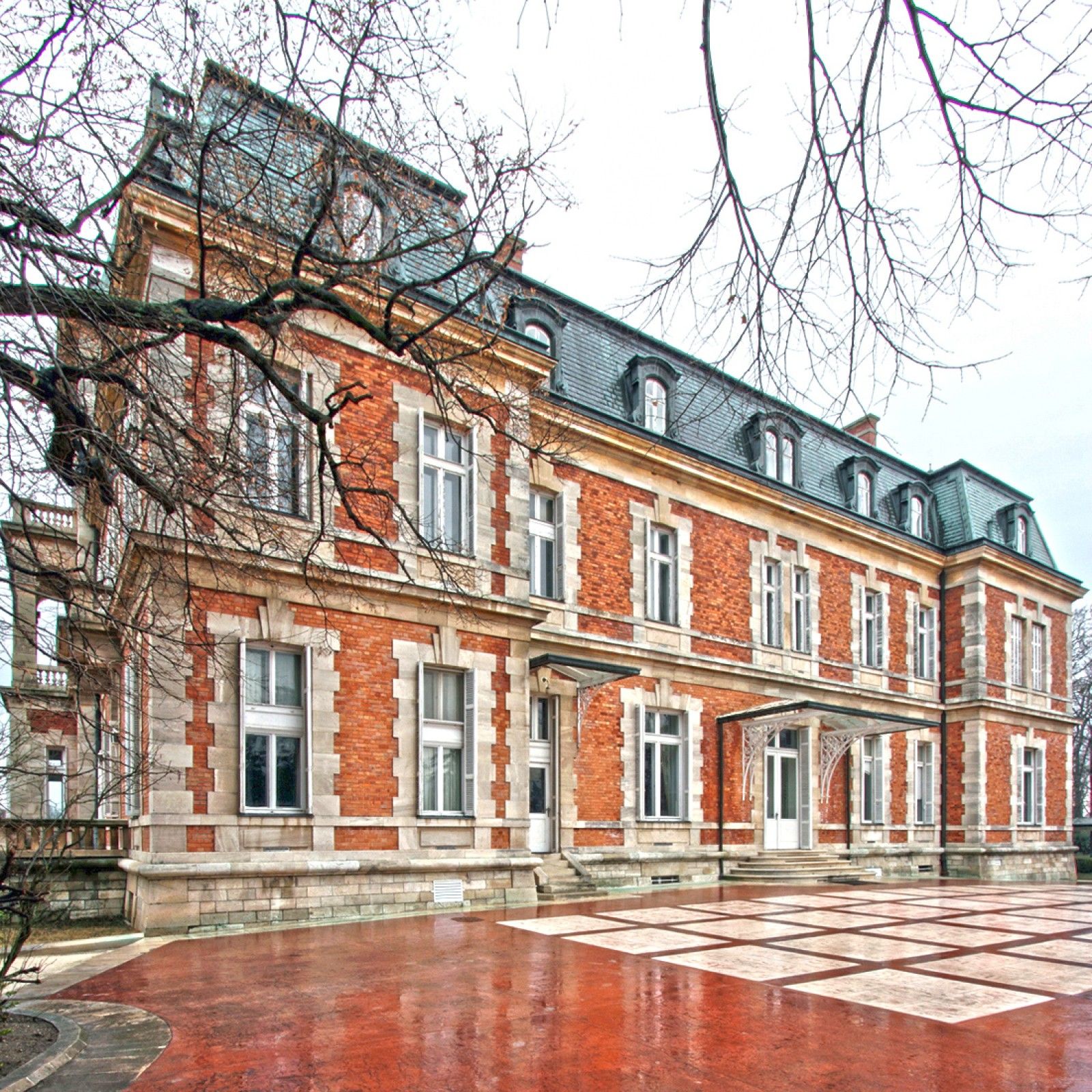 Palace in Louis XIII French château style characterized by jointed brickwork, a high mansard roof with copper cladding and a clock tower.