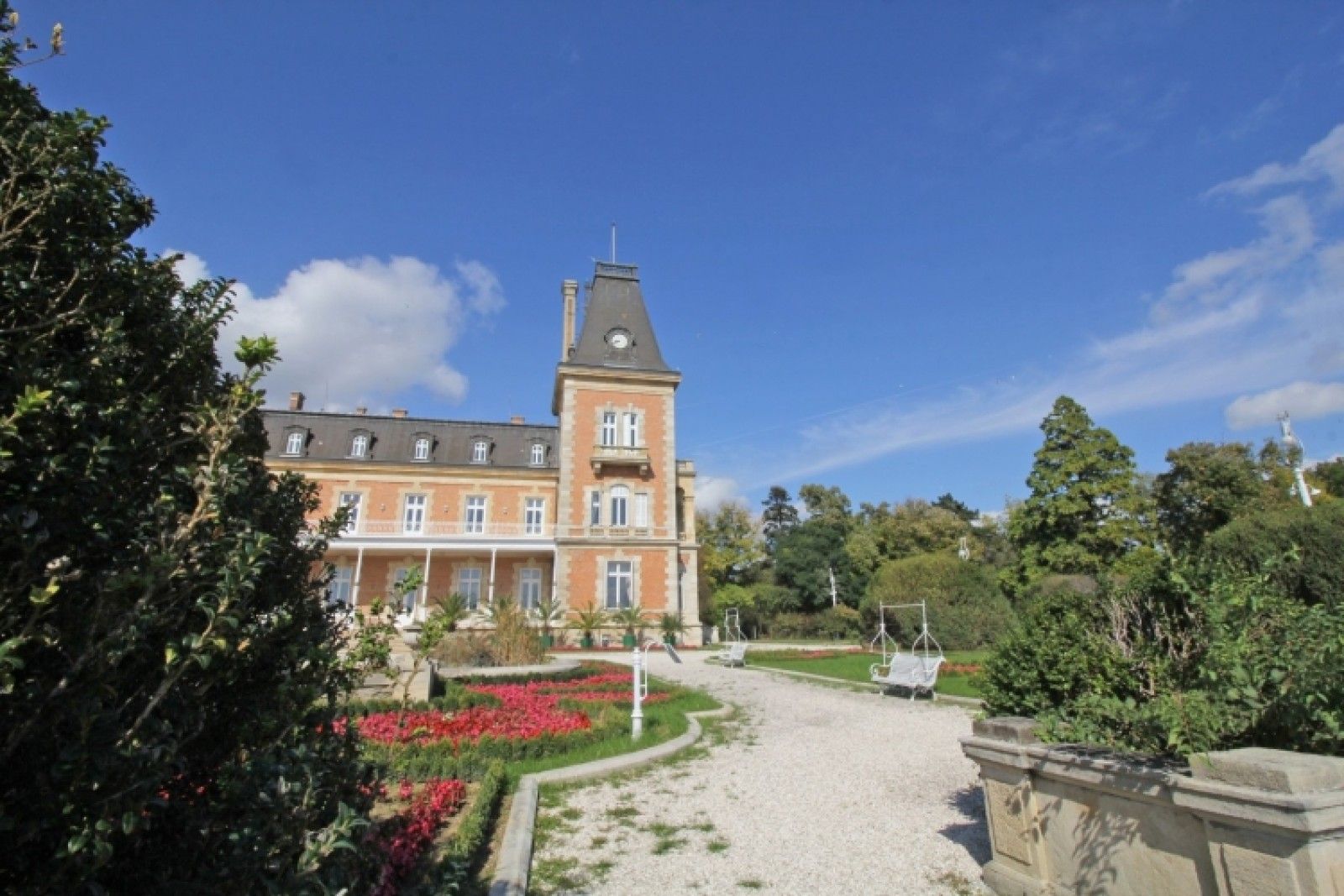 Palace in Louis XIII French château style characterized by jointed brickwork, a high mansard roof with copper cladding and a clock tower.