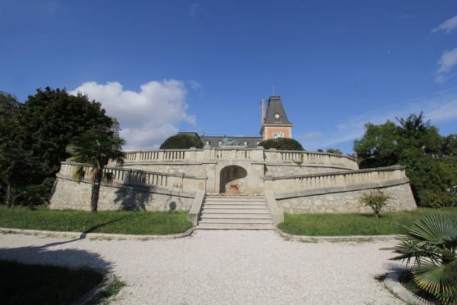 Palace in Louis XIII French château style characterized by jointed brickwork, a high mansard roof with copper cladding and a clock tower.